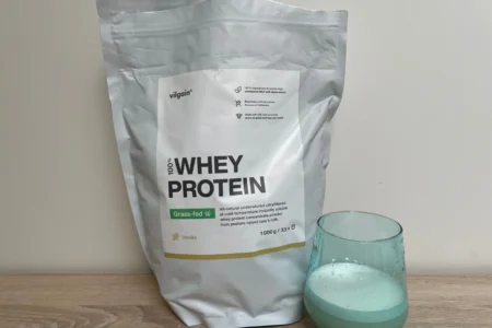 Recenze Vilgain Grass-Fed Whey Protein s příchutí vanilka, balení a sklenice s připraveným nápojem.